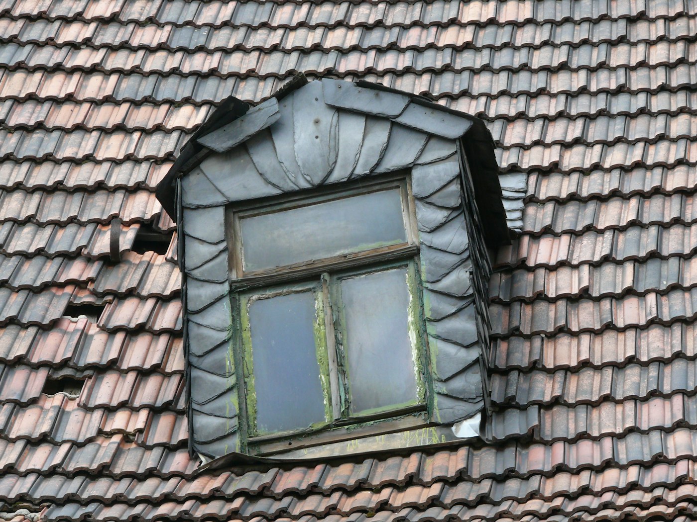 Slate-clad dormer window with intricate leadwork on a historic Atlanta roof
