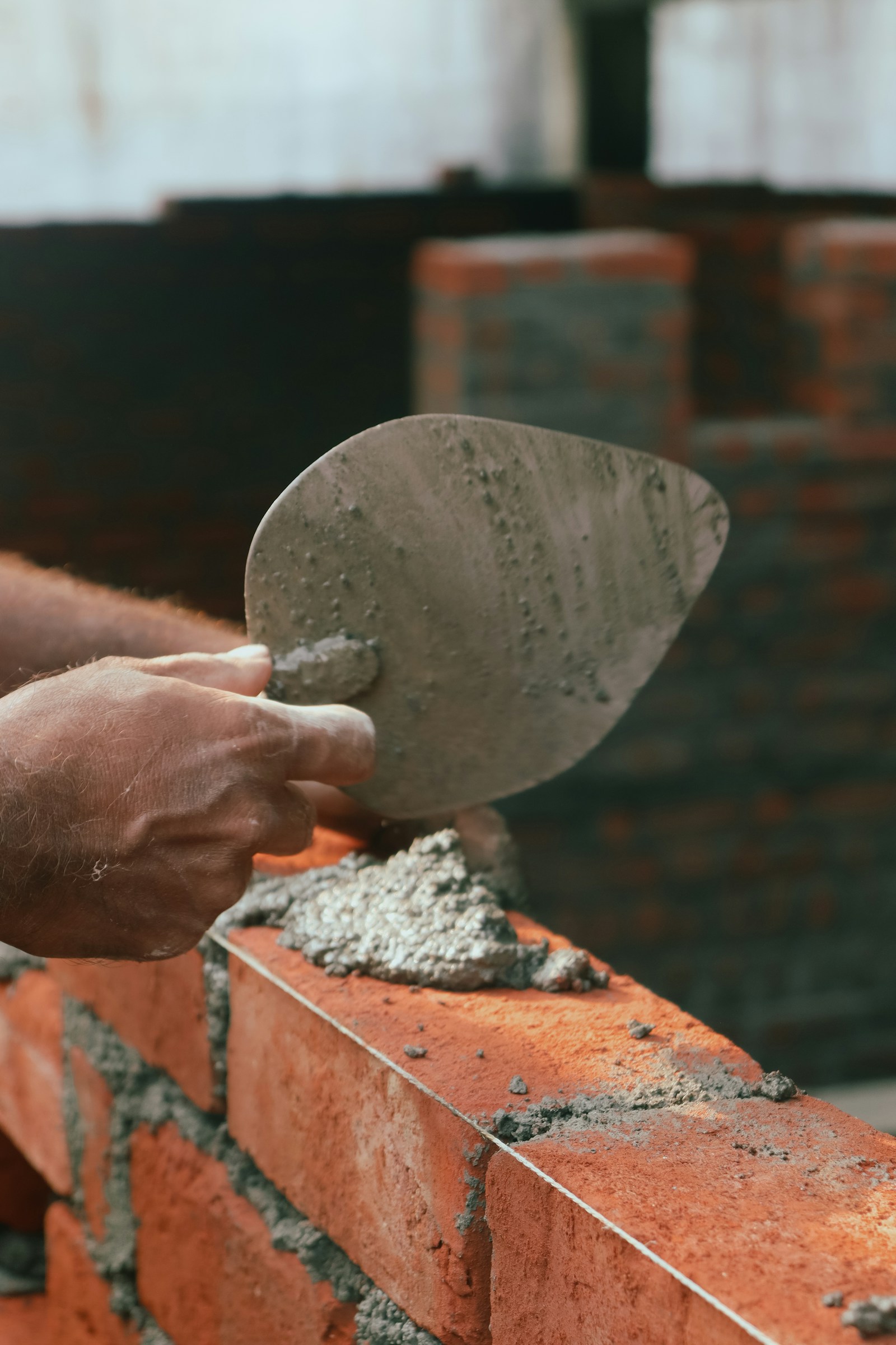 Bricklayer carefully placing a brick on a half-built retaining wall